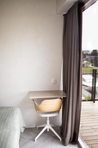 a bedroom with a desk and a chair next to a window at MARINIS Luxury Apartments - Svencelės Vėjai - 1st line by the Lagoon in Svenele
