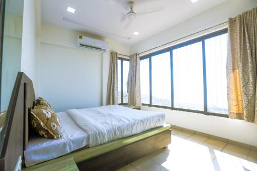 a bedroom with a bed and a large window at Daffodil by SoulStays in Dapoli