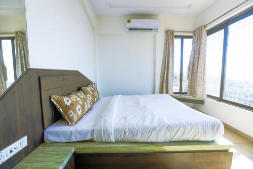 a bedroom with a bed with a bench and windows at Daffodil by SoulStays in Dapoli