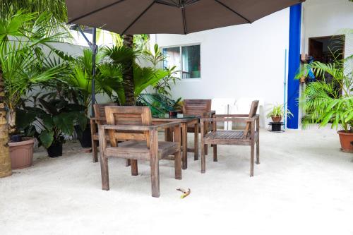 einen Holztisch und Stühle mit Sonnenschirm in der Unterkunft Palm Residence in Rasdu