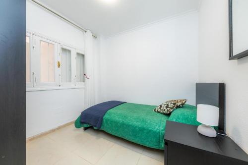ein Schlafzimmer mit einem Bett mit einer grünen Decke in der Unterkunft Dolce Vita in Alcúdia