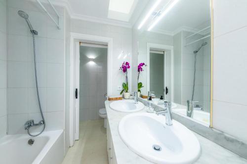 ein weißes Badezimmer mit zwei Waschbecken, einer Badewanne und einem Tubermott in der Unterkunft Dolce Vita in Alcúdia