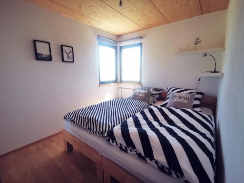 2 camas en una habitación pequeña con ventana en Ferienwohnung Heimatliebe mit Alpenblick, en Weilheim
