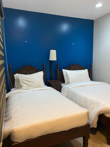 two beds in a room with a blue wall at Vivere Condominium in Vigan