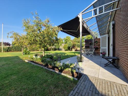 a patio with awning and a garden with plants at De Remise in Hengelo