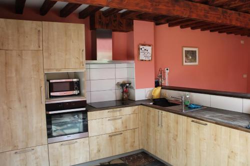 een keuken met houten kasten en een magnetron bij Chez Arsène in Bouillon