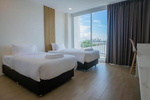 two beds in a hotel room with a large window at Hotel Agnes in Buriram