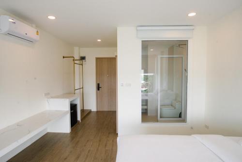 a white room with a bed and a mirror at Hotel Agnes in Buriram