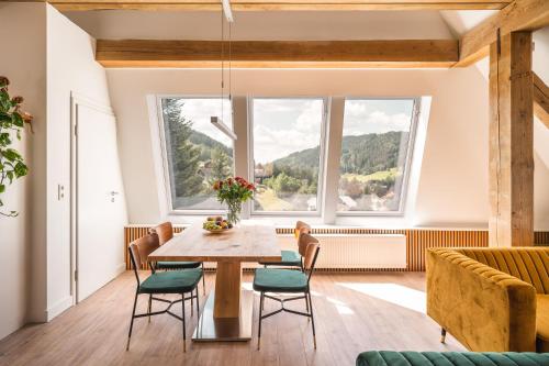 una sala da pranzo con tavolo, sedie e finestre di Hotel Großbach a Menzenschwand