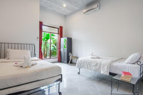 a white room with two beds and a window at Villa Kelapa in Lovina