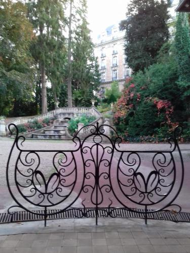 un banc assis sur un trottoir devant une fontaine dans l'établissement appartement cosy Hôtel Continental, à Vittel