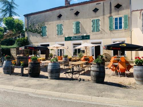 a building with tables and umbrellas in front of it at Le Chardon in Chardonnay