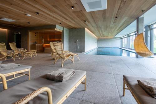 a large room with a swimming pool and chairs at Hôtel Beau Site Talloires B SPA in Talloires