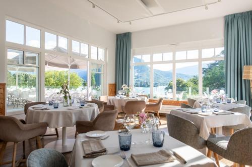 a dining room with tables and chairs and windows at Hôtel Beau Site Talloires B SPA in Talloires