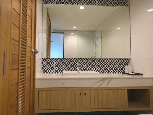 baño con lavabo y espejo grande en Sann Boutique Hotel en Chiang Rai