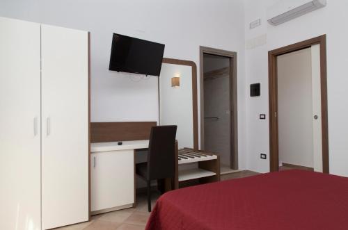 una camera da letto con scrivania, letto e specchio di Villaggio Pineta Petto Bianco a Capo Vaticano