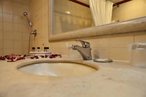 a bathroom sink with red flowers on the counter at Hotel Segredos De Vale Manso in Martinchel