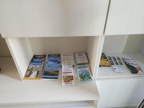a row of books sitting in a white book shelf at Casa Trekking Salento Marittima Di Diso in Marittima