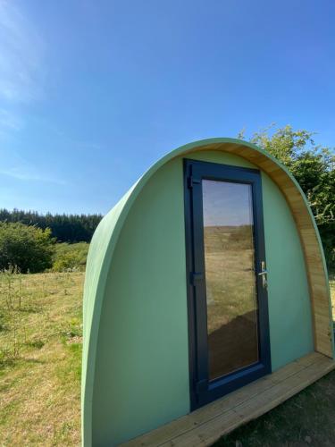 einem grünen Kuppelzelt mit einer Tür auf einem Feld in der Unterkunft Lakeside Eco Pod in Oswestry