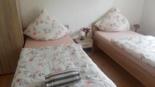 2 Betten in einem kleinen Zimmer mit Blumen in der Unterkunft Zimmervermietung Pargen in Daun