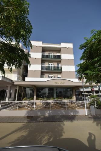 un grand bâtiment blanc avec un parking en face de celui-ci dans l'établissement Hotel Eden, à Bellaria-Igea Marina