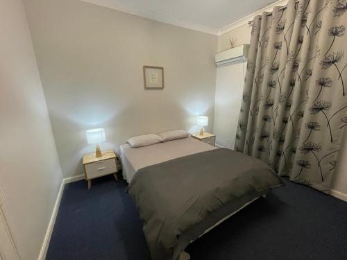a small bedroom with a bed and two lamps at The Pink House in Walgett