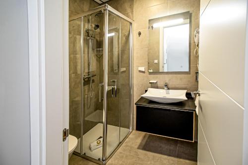 W łazience znajduje się szklana kabina prysznicowa i umywalka. w obiekcie Apartamentos Ribera 19 w Kordobie