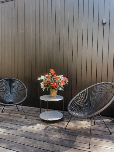two chairs and a table with a vase of flowers at Camping Milk in Usmenieki