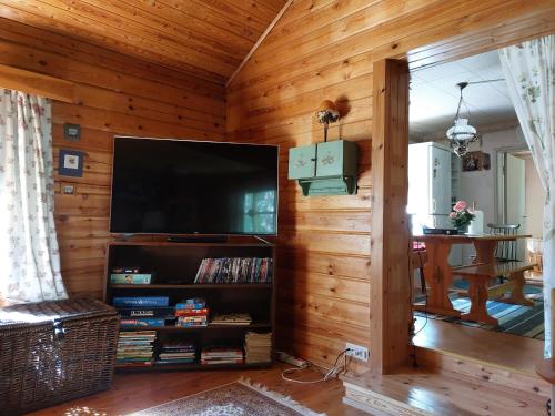 sala de estar con TV grande en una pared de madera en Idyllinen mökki Laitilassa, en Laitila