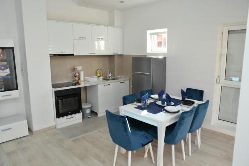 uma cozinha com uma mesa branca e cadeiras azuis em Stan na dan Raška em Raška