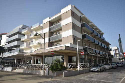 un bâtiment avec des voitures garées devant lui dans l'établissement Hotel Eden, à Bellaria-Igea Marina