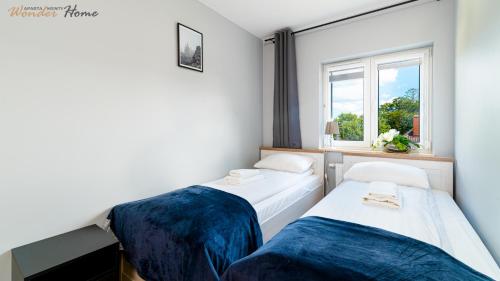 two beds in a room with a window at Wonder Home - Apartament Blue z widokiem na góry - przy szlakach turystycznych i stokach narciarskich in Karpacz