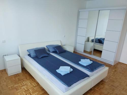 a bedroom with a large bed with blue pillows and a mirror at Apartman Blok 45 (reka Sava) in Belgrade