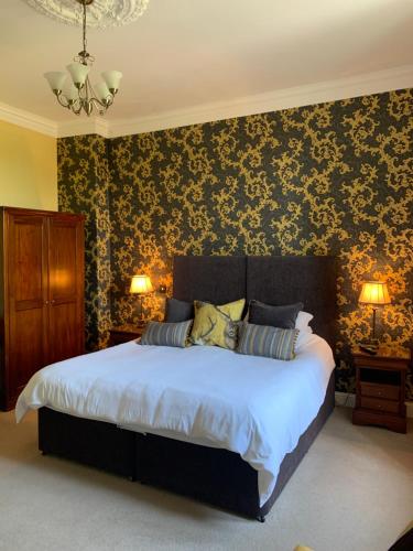 a bedroom with a large bed with floral wallpaper at Creity Hall Guest House in Doune