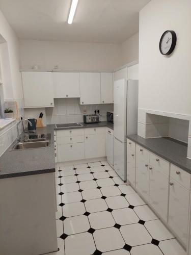 a kitchen with white cabinets and a clock on the wall at The York Riverside Suites in York