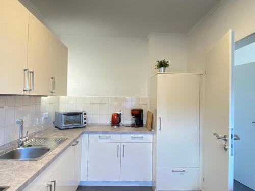 a white kitchen with a sink and a microwave at Försters Ferienhaus in Atzelgift
