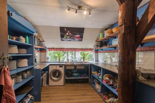 a kitchen with blue shelves and a washer and dryer at De Linde, boerderij in Drenthe voor 15 tot 30 personen in Linde