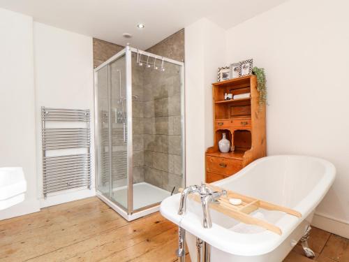 een badkamer met een douche en een wit bad bij The Water House in Falmouth