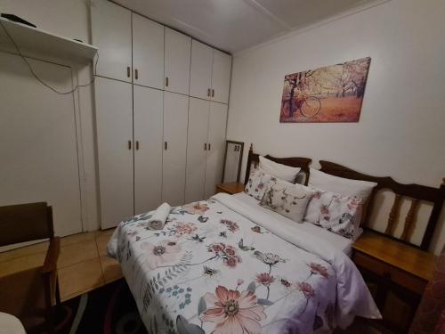 a bedroom with a bed with a floral bedspread at Zenith House Boston Self Catering Accomodation in Cape Town