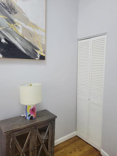 a room with a table with a lamp and a painting at The Harlem Getaway in New York