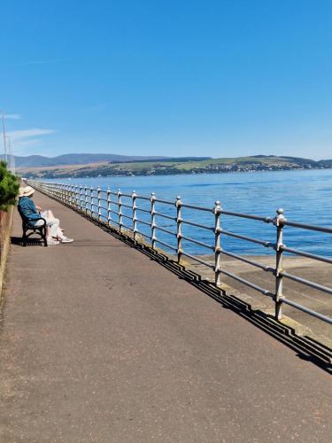 a person sitting on a bench next to the water at Firthview House in Kirn