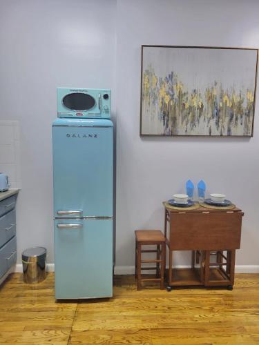 a kitchen with a refrigerator and a table with a painting at The Harlem Getaway in New York