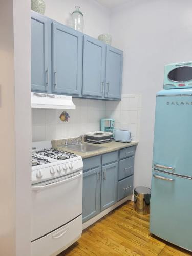 a kitchen with blue cabinets and a white stove and refrigerator at The Harlem Getaway in New York