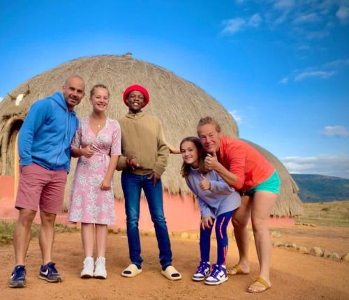 a group of people standing in front of a thatch hut at Swazi Dreams. (Nqabaneni Eco-Volunteering.) in Usutu