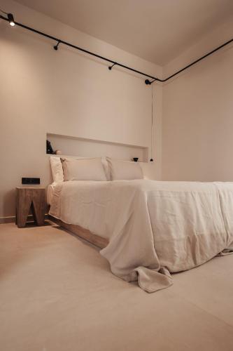 a white bedroom with a large bed with white sheets at Om Living Afitos in Afitos