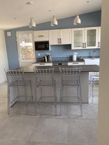 une cuisine avec trois tabourets de bar et un comptoir dans l'établissement La Maison du Vieux Port, à Flamanville