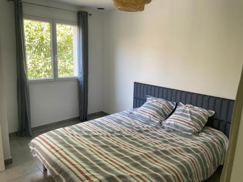 1 dormitorio con 1 cama con edredón de rayas y 2 ventanas en Magnifique villa avec piscine en Provence, en Bédarrides