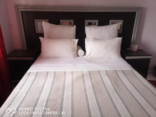a large bed with white sheets and pillows at Pearl Guest House Vanderbijlpark Johannesburg in Vanderbijlpark