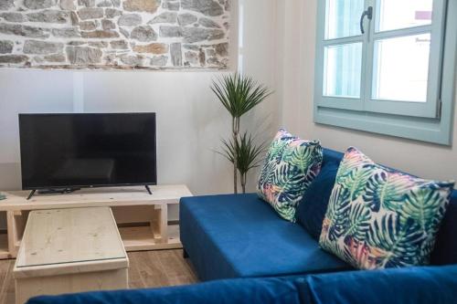 um sofá azul numa sala de estar com uma televisão em Agiopetra Lofts em Kavala