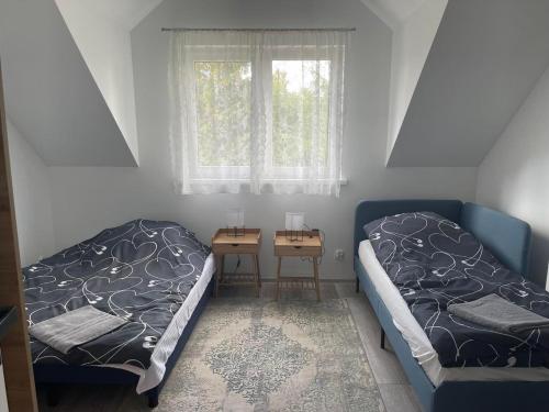 1 dormitorio con 2 camas, mesa y ventana en Zakątek Wenantego Apartament en Kopalino